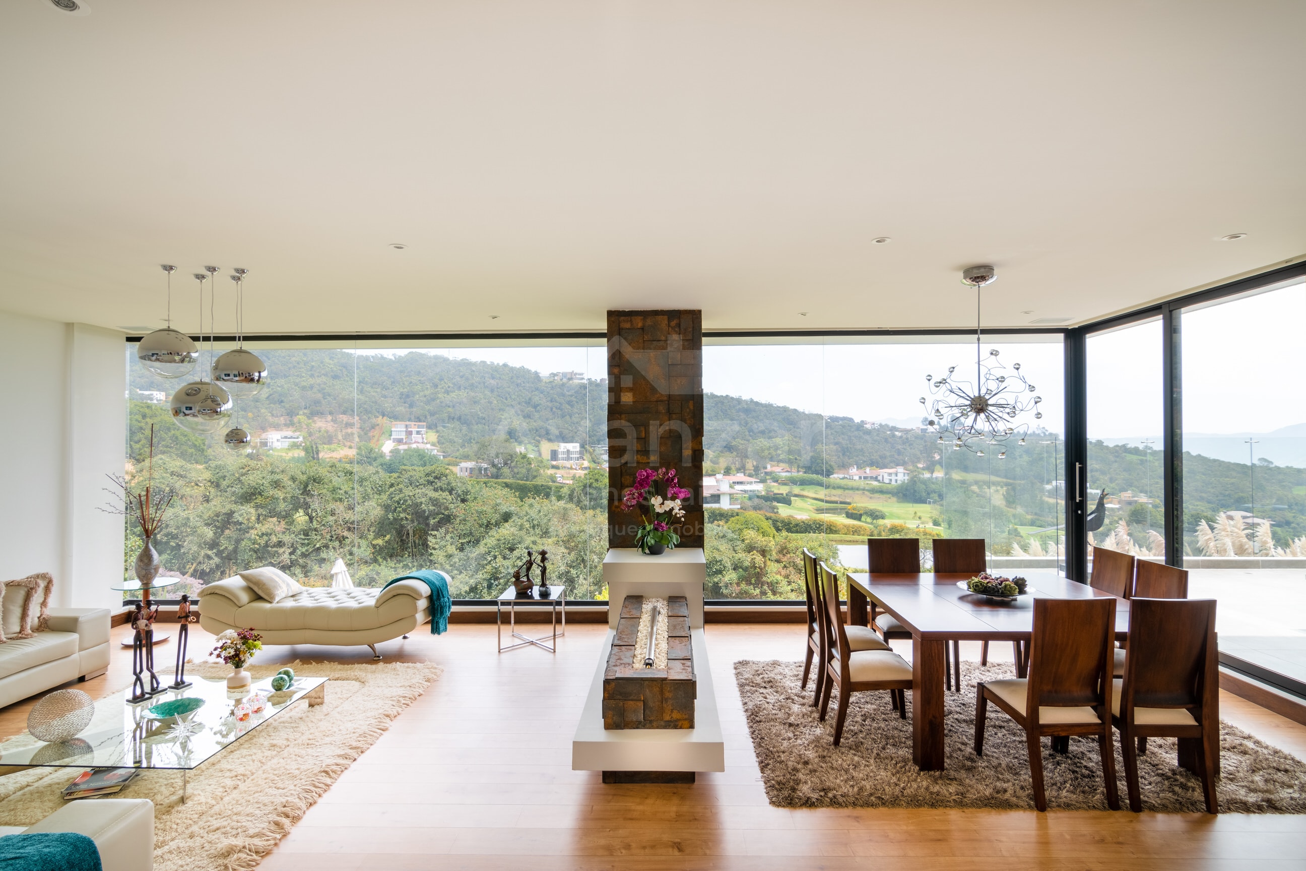 Sala y comedor de planta abierta con ventanales de piso a techo que exhiben una vista panorámica del campo de golf y el Valle de Sopó.