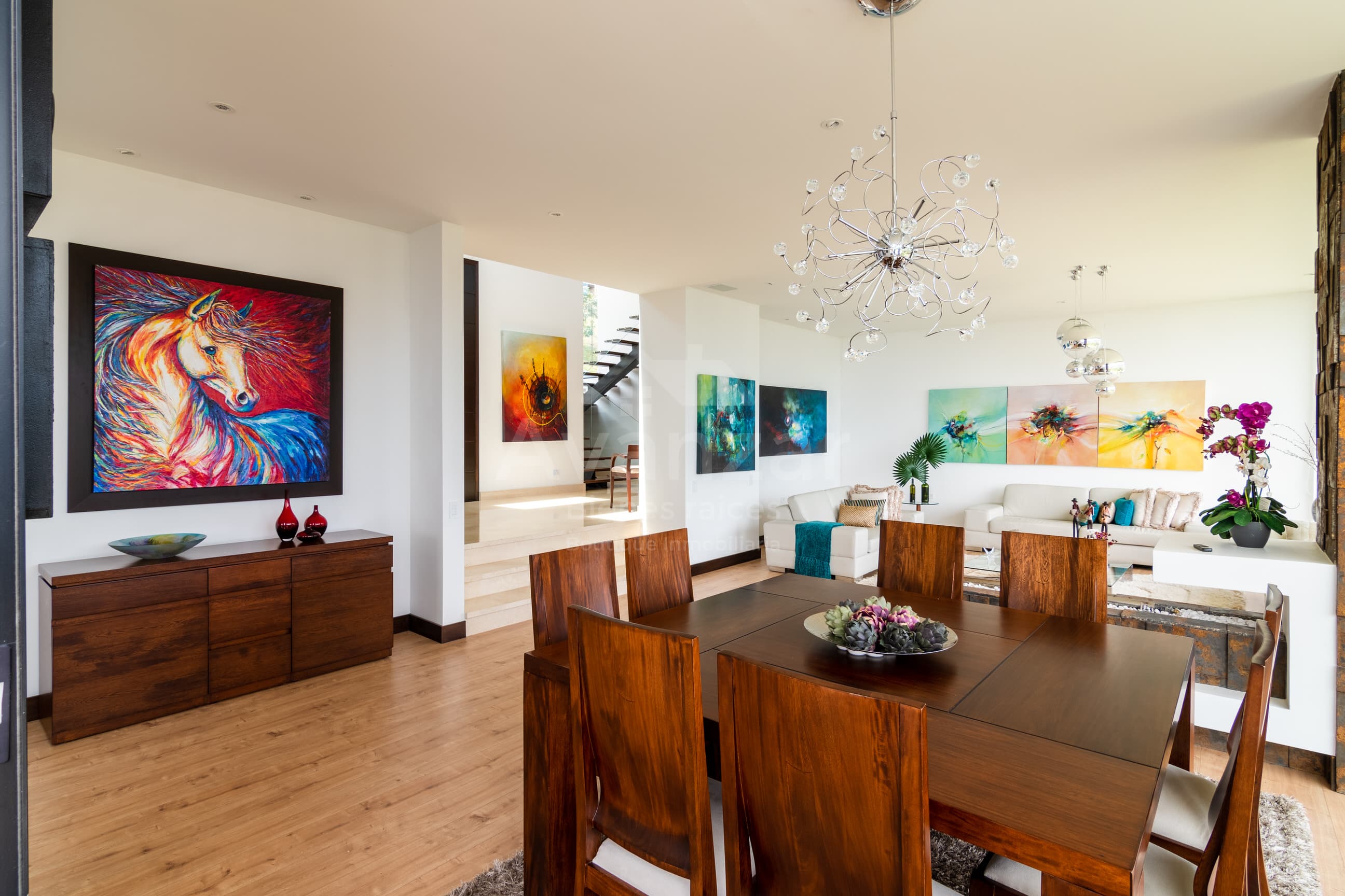 Comedor en madera maciza integrado a la sala, con lámpara de cristal
