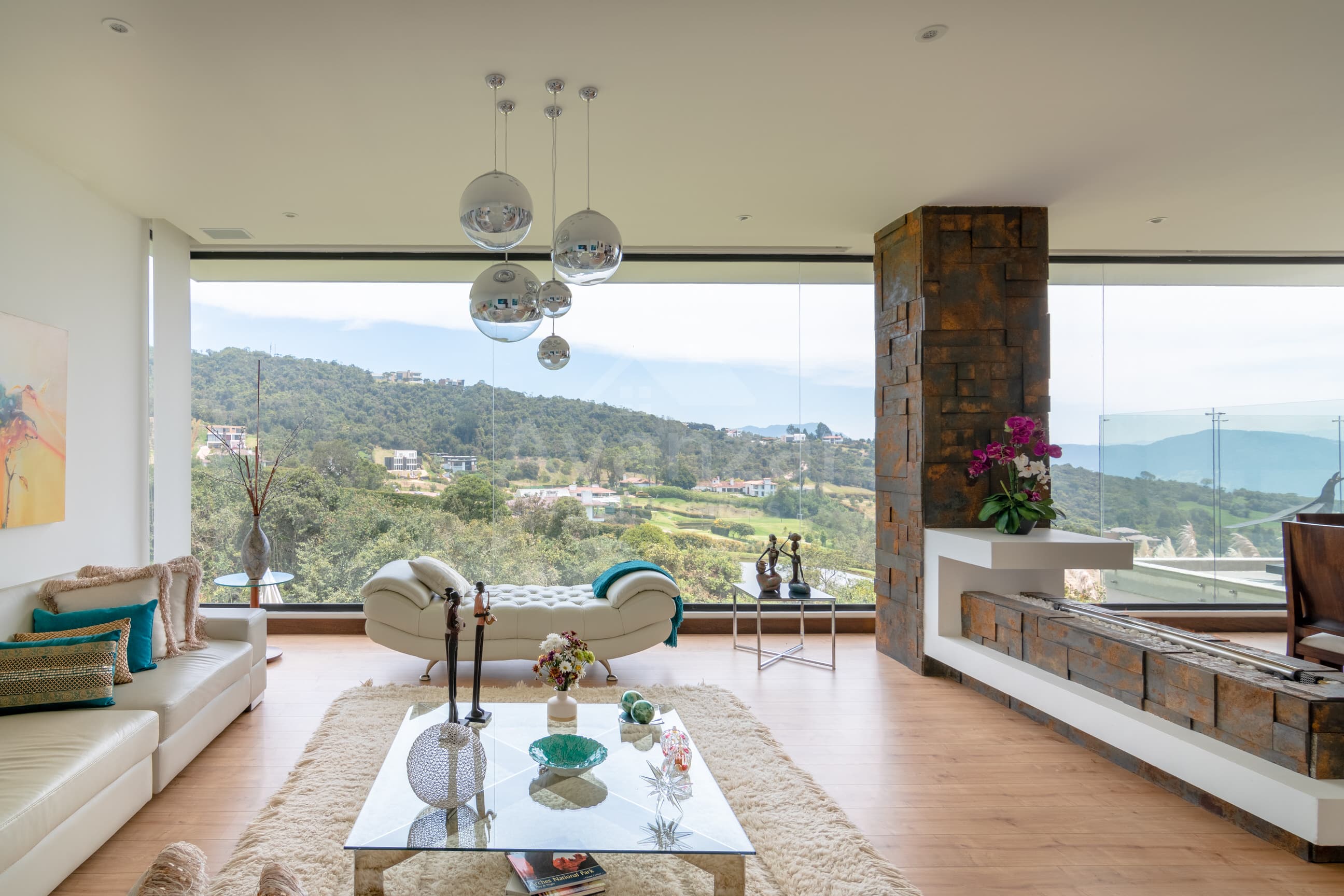 Sala de doble altura con chimenea en piedra y vista panorámica al campo de golf