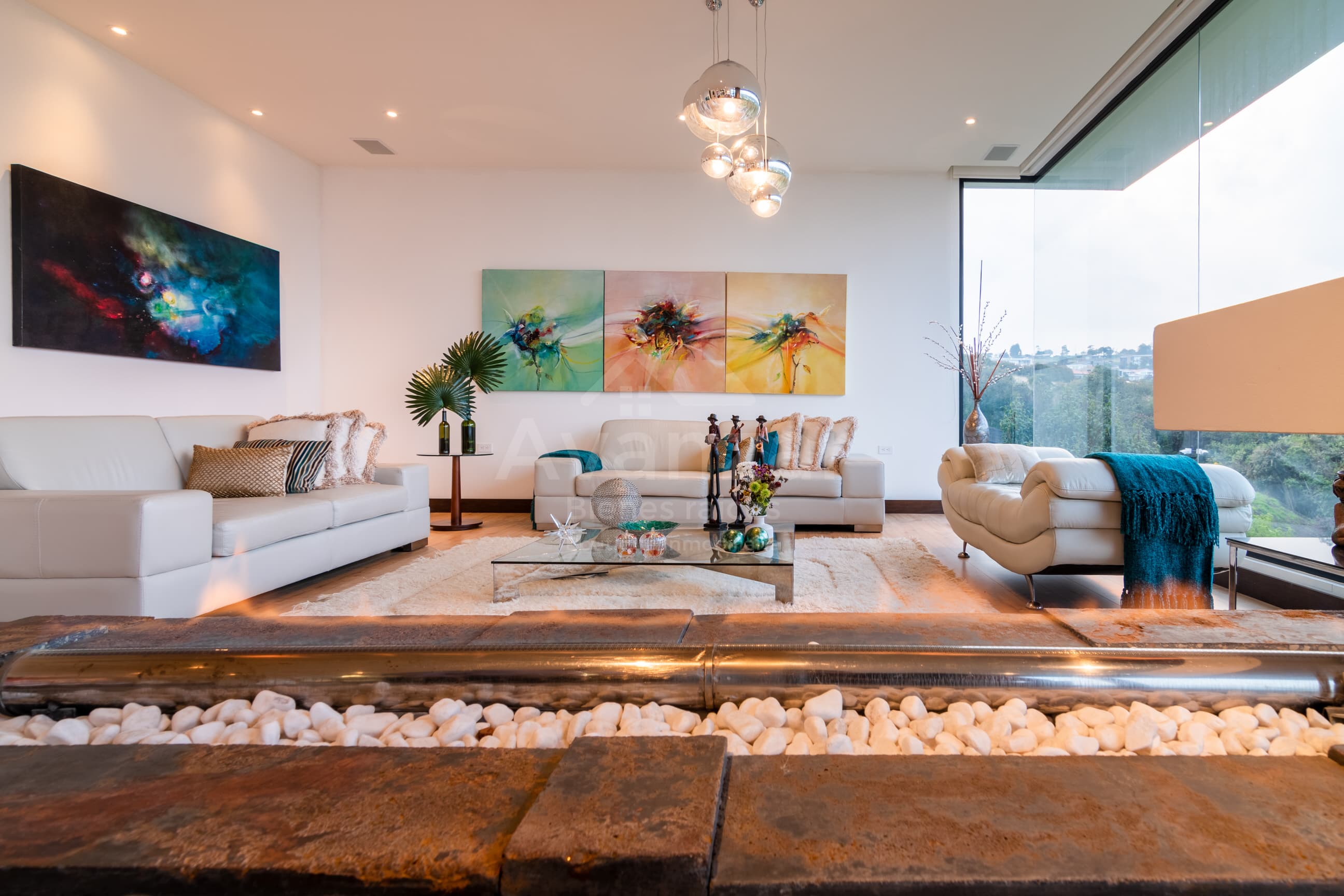 Sala de estar con sofás de cuero, arte abstracto y vista a las colinas del valle